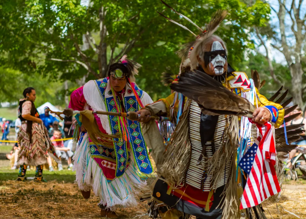 two people in traditioan Native outfits and face paint perform
