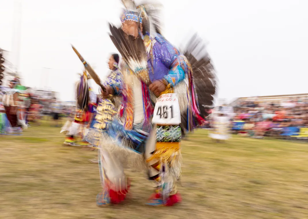 a Native American elder performs in traditional garb