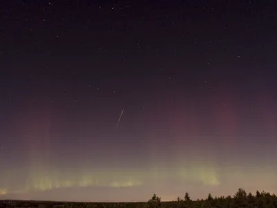 A Draconid meteor streaks across the sky as the northern lights glow, as seen from north of Stockholm on October 8, 2011.