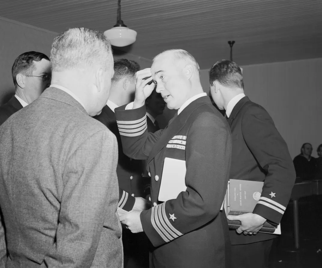 Captain Charles B. McVay III (center, with hand touching forehead) attends his Navy court martial in December 1945.