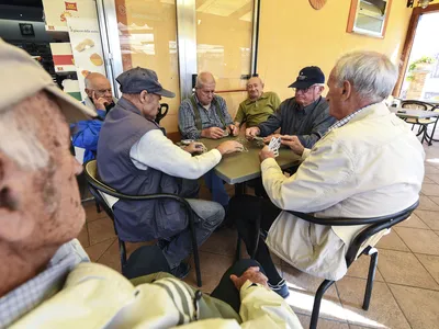 A group of old men playing cards in a bar in Acciaroli, southern Italy, in 2016. The town&nbsp;has a disproportionately high number of centenarians.